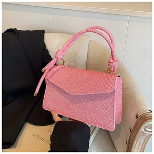 Pink striped crossbody bag with creative rope knot handle detail on a vintage sofa