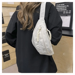 Detailed view of white nylon chest bag with embroidery and braided zipper pull details