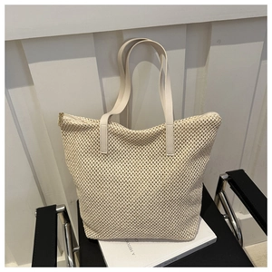 Dettaglio della borsa tote in paglia beige con spallacci lisci e cerniera in metallo