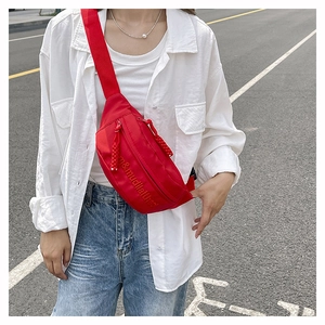 Close-up of stylish red nylon crossbody chest bag with embossed lettering and wide strap