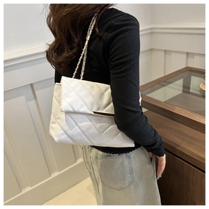 Detailed side view of white quilted crossbody bag with gold metal trim on model