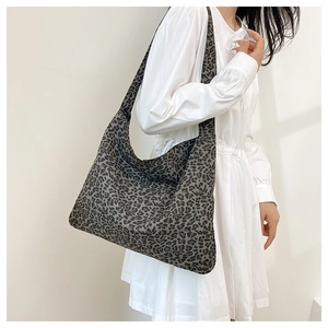 Lifestyle shot of large leopard print tote bag styled with white dress and soft shadows