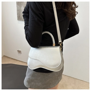 Detail of silver saddle bag showing the woven handle and unique wavy flap design