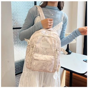 Side view of a cream school backpack featuring hand-drawn bear patterns on nylon fabric