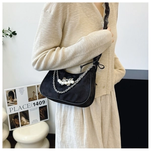 Detail of black crescent shoulder bag with silver chain, white pearls and bow charm
