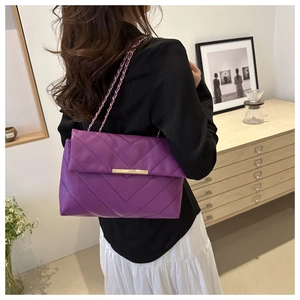 Detail of purple V-quilted faux leather shoulder bag with golden metallic chain strap