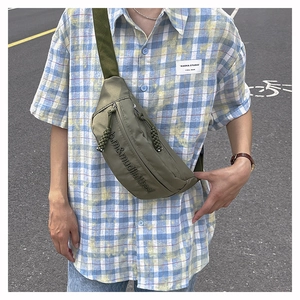 Detail of army green nylon chest bag with embossed lettering and braided zipper puller
