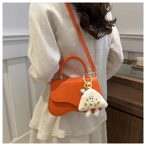 Detail of orange wave bottom crossbody bag with cute plush pendant on a female model