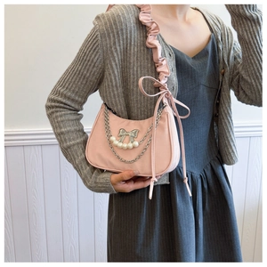 Detailed shot of pink crescent bag featuring silver bow, pearls and ruffled shoulder strap