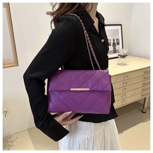 Detail of purple crossbody bag featuring chevron stitching and gold metal lock hardware