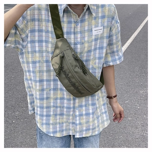 Detail of army green nylon crossbody bag with zipper pull and letter print design