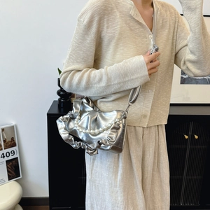 Sac croissant argenté plissé avec chaîne de perles porté à l'épaule par un mannequin