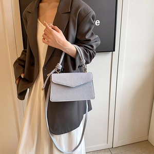Elegant light blue textured crossbody bag with woven rope handles and gold rings