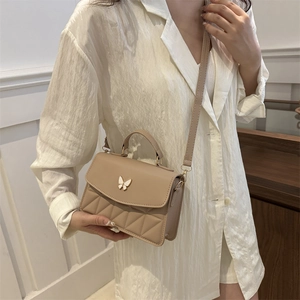 Elegant apricot leather handbag with a metal butterfly clasp and quilted pattern detail