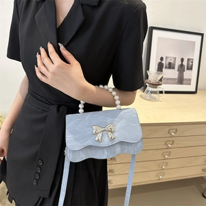 Light blue crossbody bag with pearl handle and silver butterfly detail on front