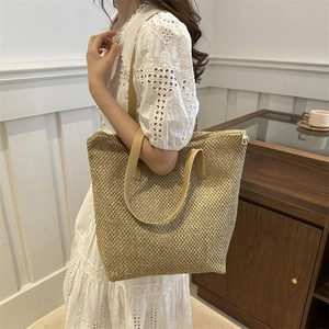 Borsa tote in paglia intrecciata con manici in pelle indossata da una modella