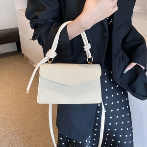 Chic cream twill crossbody bag with unique knotted handle and adjustable shoulder strap
