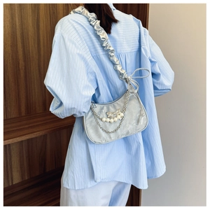 Silver crescent underarm bag with decorative pearl chain and metal bow charms detail