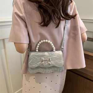 Silver crinkled leather handbag with pearl handle and metal bow on pink outfit