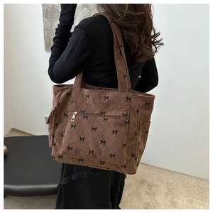 Brown corduroy tote bag with bow prints and quilted stitching worn by model