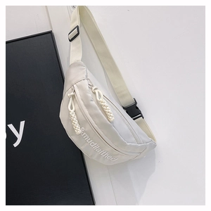 Detail of ivory nylon chest bag featuring mudilaithed embroidery and woven zipper pulls