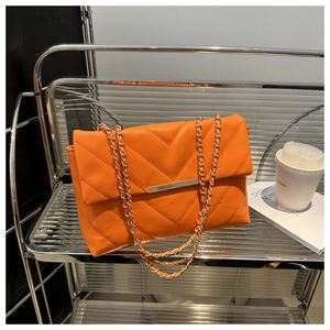 Detail of orange chevron quilted bag with gold metal latch and chain strap