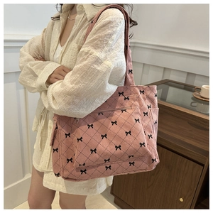 Pink corduroy tote bag with black bow details and diamond pattern on the surface