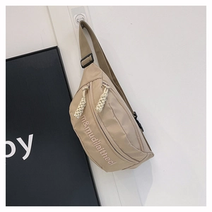 Close-up of beige nylon crossbody bag featuring letter embroidery and woven zipper pulls