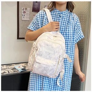 Detail of white mini backpack featuring gray bear prints and durable fabric on model