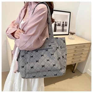 Detail of grey corduroy tote bag with black bow print and diamond quilted stitching patterns