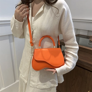 Bright orange small square bag with woven handle and wavy base, styled as a crossbody