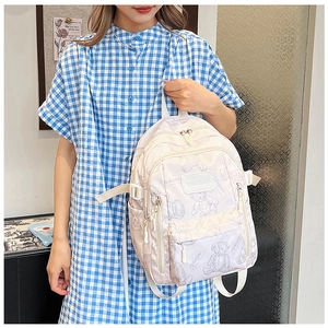 Girl wearing a cream white backpack with purple bear prints and adjustable straps