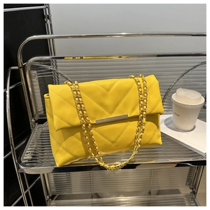 Close-up of vibrant yellow V-quilted faux leather bag with elegant gold chain strap