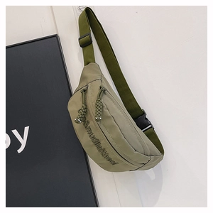 Detail of olive green nylon crossbody bag showing embroidery and dual zipper compartments