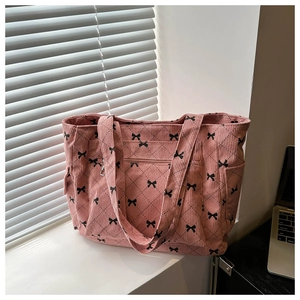 Pink corduroy tote bag detail with quilted diamond pattern and black bow print