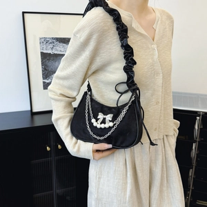 Black underarm bag with pearl bow charm and scrunchie shoulder strap in minimalist style