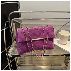 Detail of purple V-quilted faux leather bag with gold buckle on a stylish metal shelf