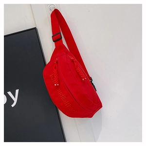 Detail of red crossbody bag showing textured embossed text and woven zipper puller