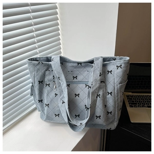 Close-up of light blue corduroy tote bag with bow pattern and quilted storage pockets
