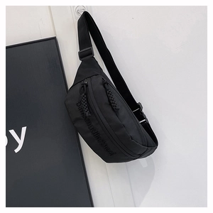 Close-up of black nylon crossbody bag featuring embossed letters and woven rope zippers
