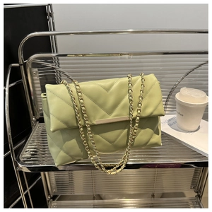 Detail view of light green chevron quilted bag with golden chain and metal buckle
