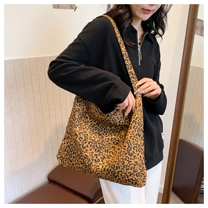 Large leopard print tote bag worn by a model in a casual, minimalist indoor setting