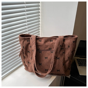 Close-up of brown corduroy tote bag with black bow print and quilted rhombus pattern