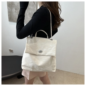 Close-up of white crossbody bag featuring paper-like texture and silver metal twist lock