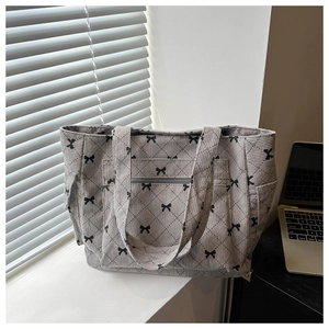 Detail of light gray corduroy tote bag with black bow patterns and side pockets
