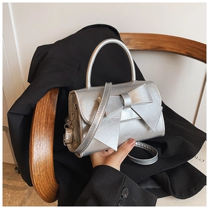 Close-up of a silver bow handbag featuring a metallic PU finish and elegant top handle