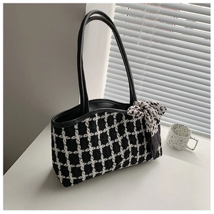 Detail of tweed tote bag with black leather handle and polka dot scarf accessory