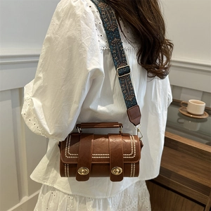 Sac bandoulière cylindrique marron avec coutures blanches et sangle brodée bohème