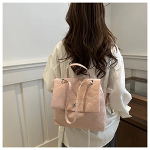 Detail of light pink pleated backpack featuring silver twist-lock closure and slim straps