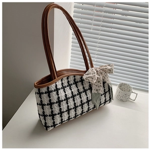 Detail of checkered tote bag with brown faux leather strap and decorative silk scarf bow